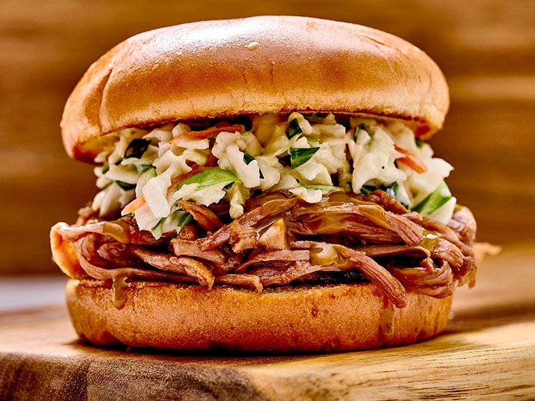Sonny's Sweet Carolina sandwich piled high with tender pulled pork, homemade coleslaw, and tangy Carolina mustard BBQ sauce on a toasted brioche bun